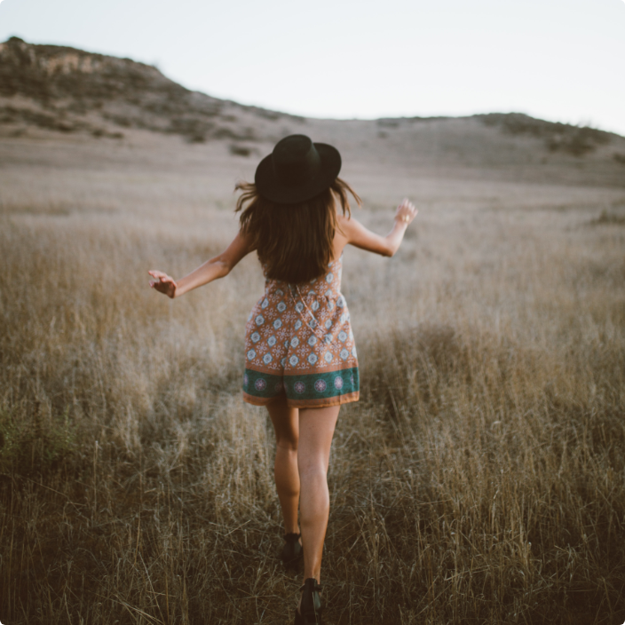 photo of girl running through a path in the field